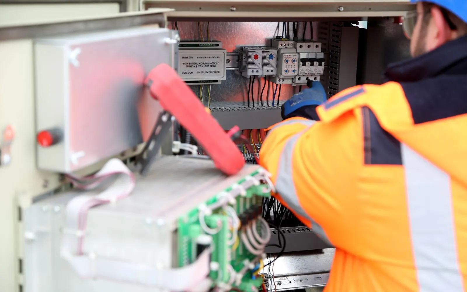 Électricien professionnel intervenant sur un tableau électrique industriel en tenue de sécurité