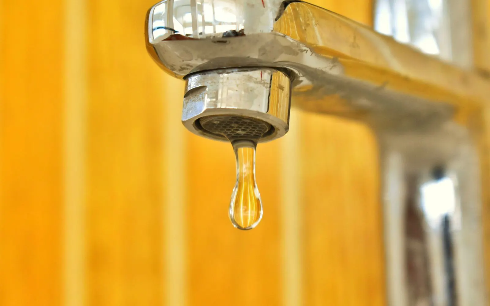 Goutte d'eau qui perle au bout d'un robinet, signe d'une fuite d'eau à ne pas négliger