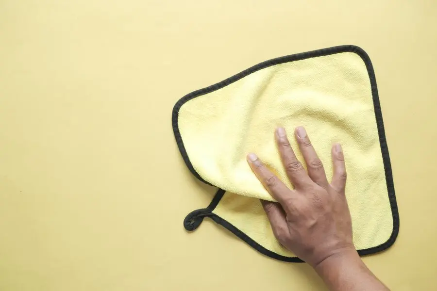 Main qui éponge une flaque d'eau avec un chiffon pendant l'attente du plombier