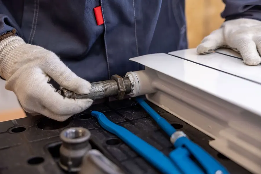 Plombier professionnel réparant un tuyau de radiateur avec des outils spécialisés