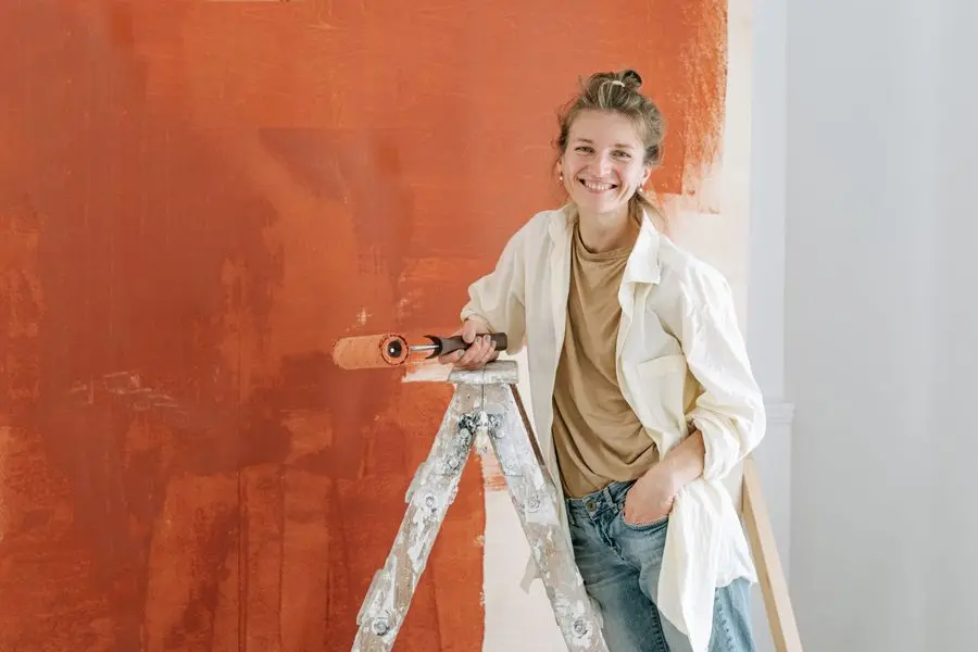 Peintre appliquant un rouleau de peinture colorée sur un mur intérieur